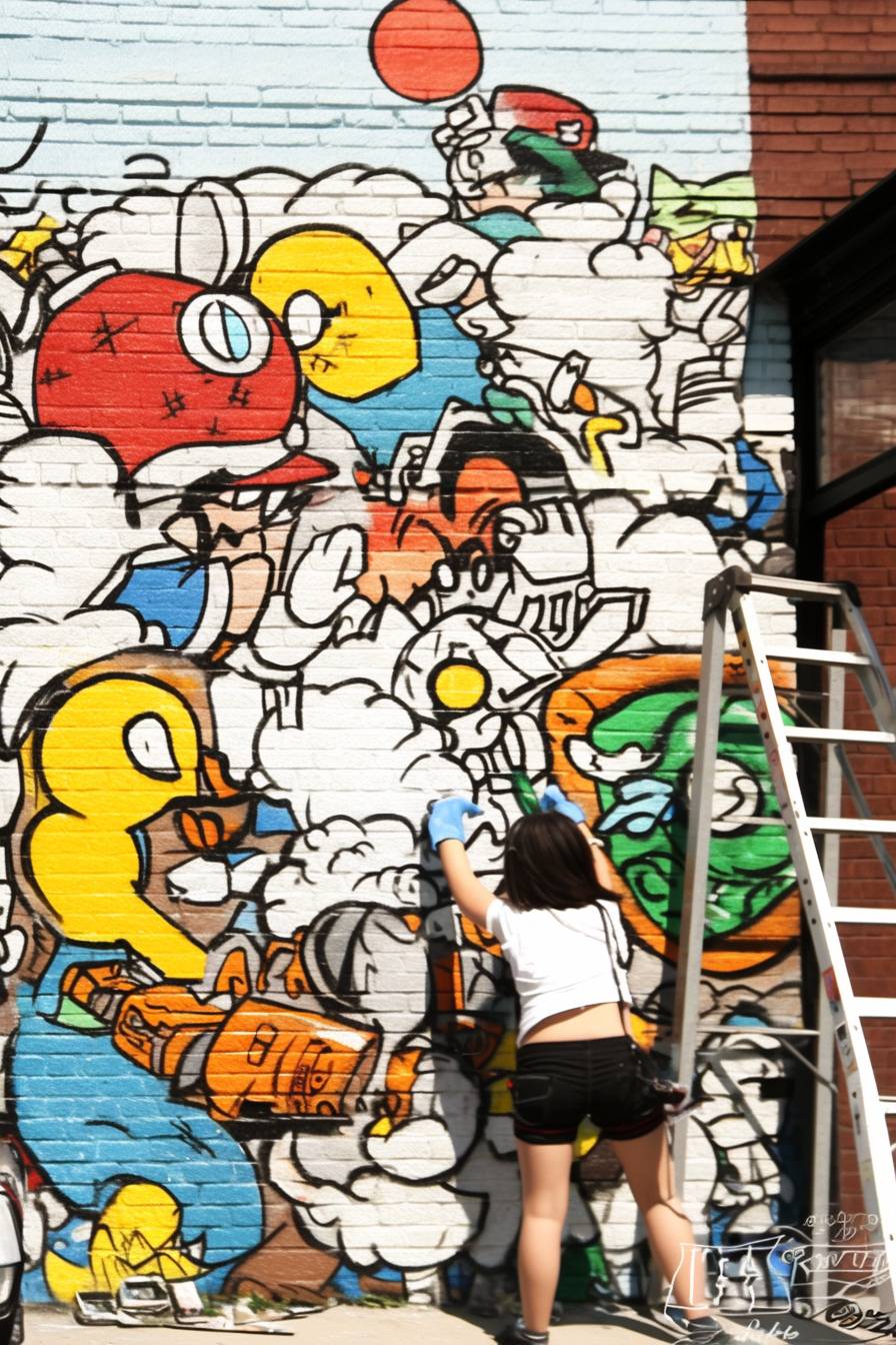 A vibrant street art scene with a girl painting a colorful mural on a brick wall, capturing a lively and creative urban environment